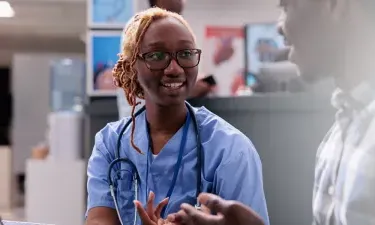 Oklahoma medical assistant smiling and discussing treatment with patient in clinic